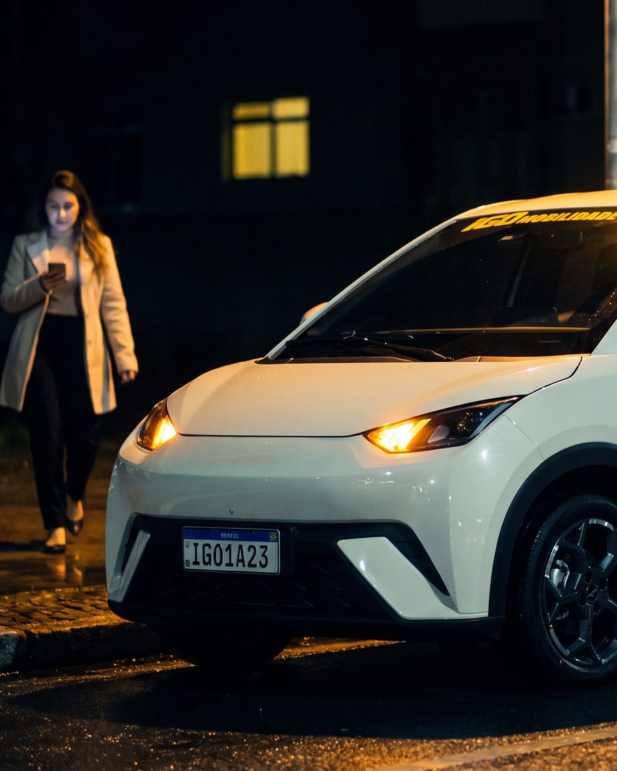 Passageira caminhando até um carro da frota iGO Mobilidade à noite em Bauru